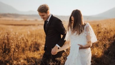 shallow focus photo of man in black formal suit holding woman s hand in white dress