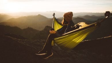 unrecognizable woman sitting in hammock above mountains