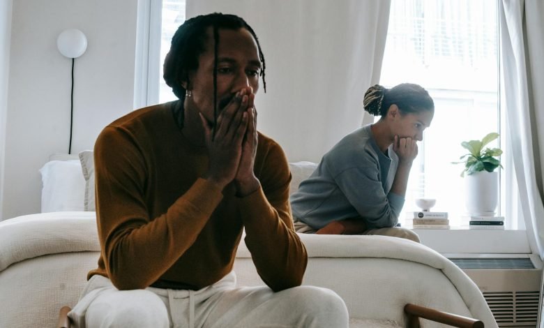 unhappy black couple sitting on bed after having argument